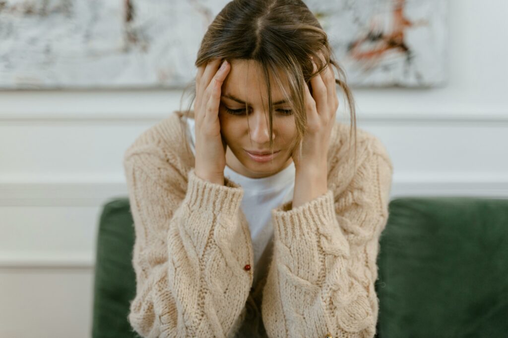 Femme assise, la tête dans les mains, expression de détresse — illustration de l’anxiété