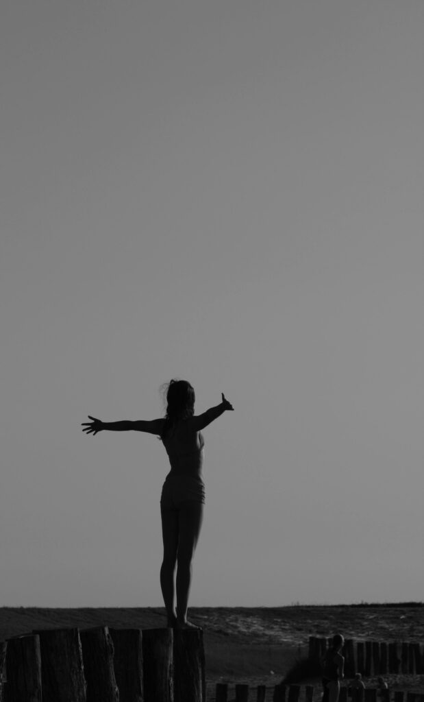 Silhouette féminine en noir et blanc levant les bras, image de libération de la charge mentale