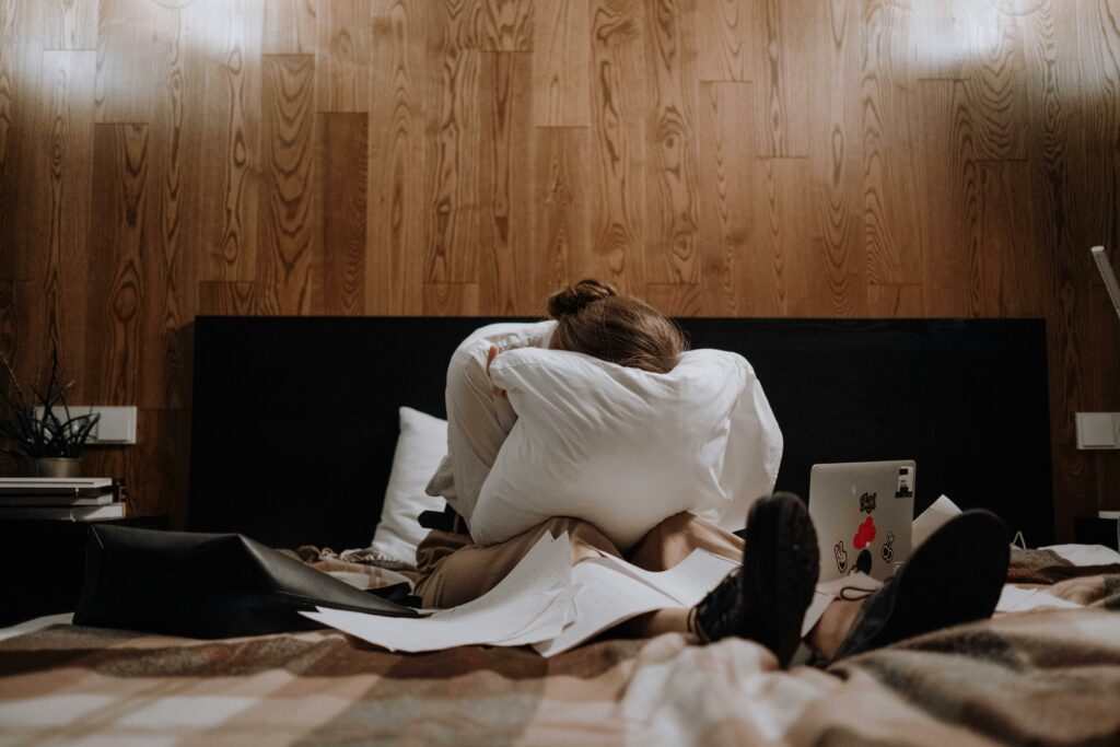 Femme recroquevillée sur son lit, à bout, symbole des troubles liés à la surcharge mentale