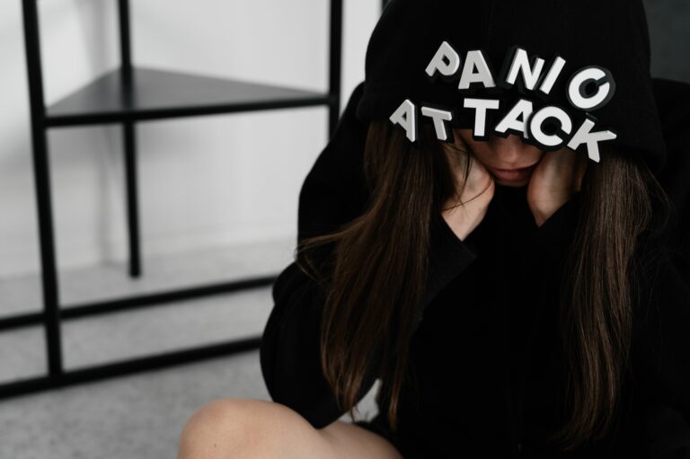 Femme anxieuse assise sous une capuche portant l’inscription Panic Attack